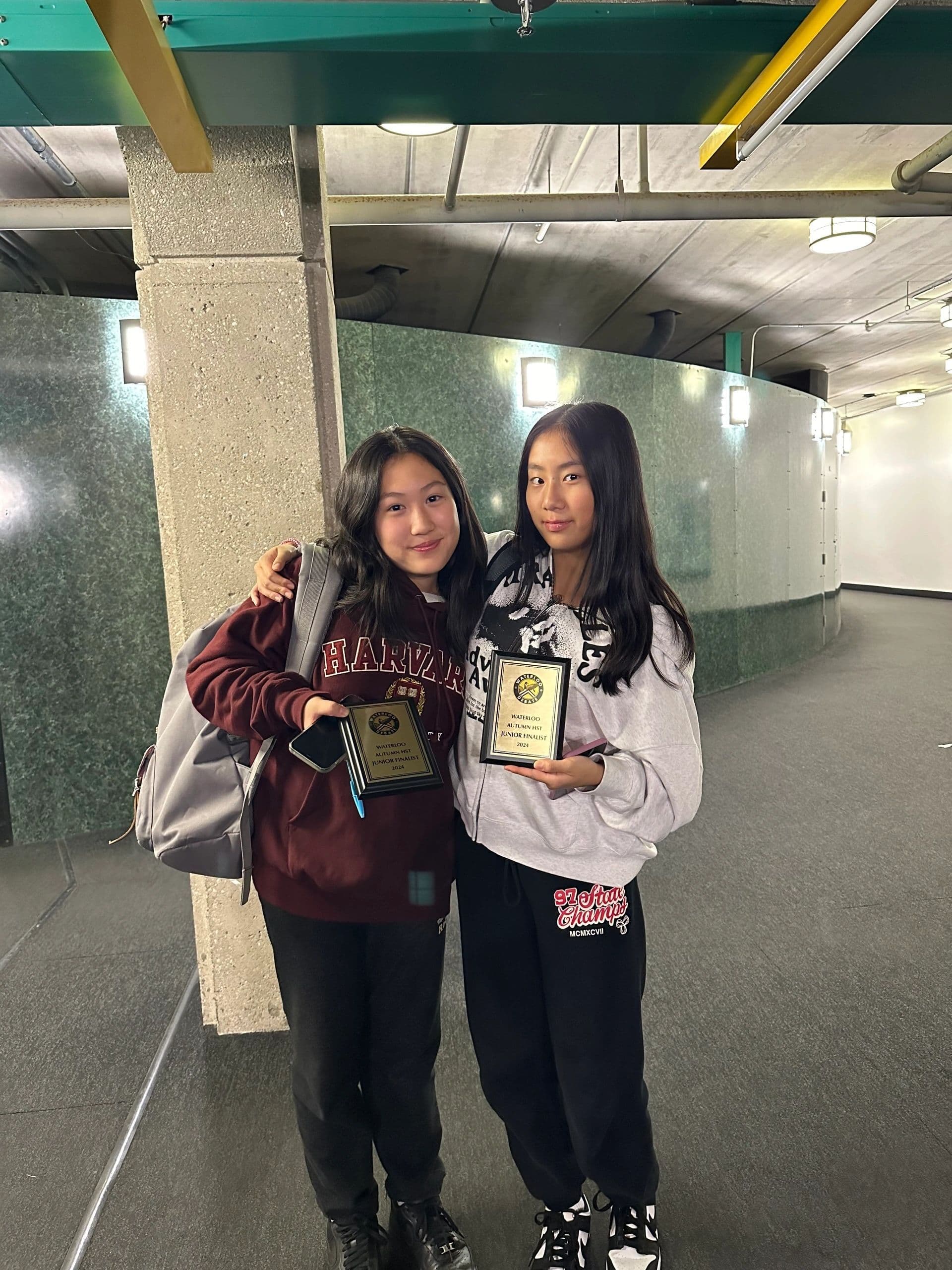 Two Young Voices debaters holding tournament plaques.